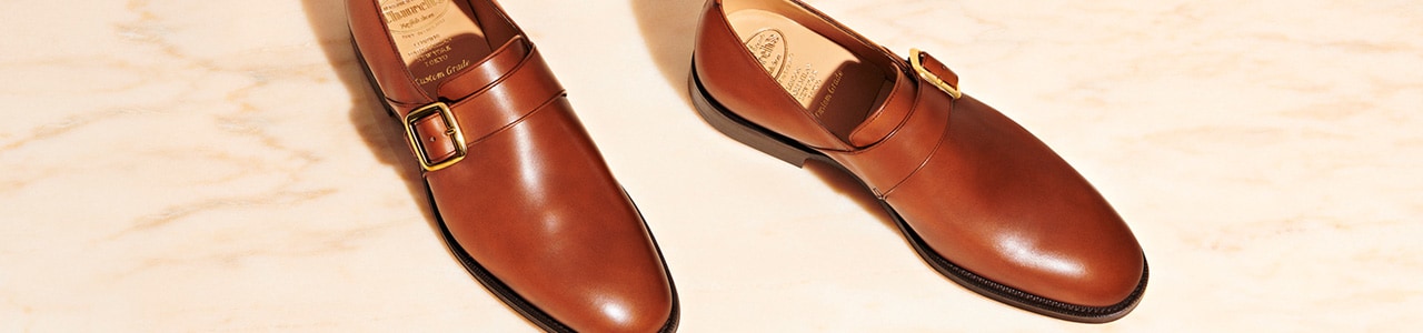 Black leather monk strap shoes against blue background
